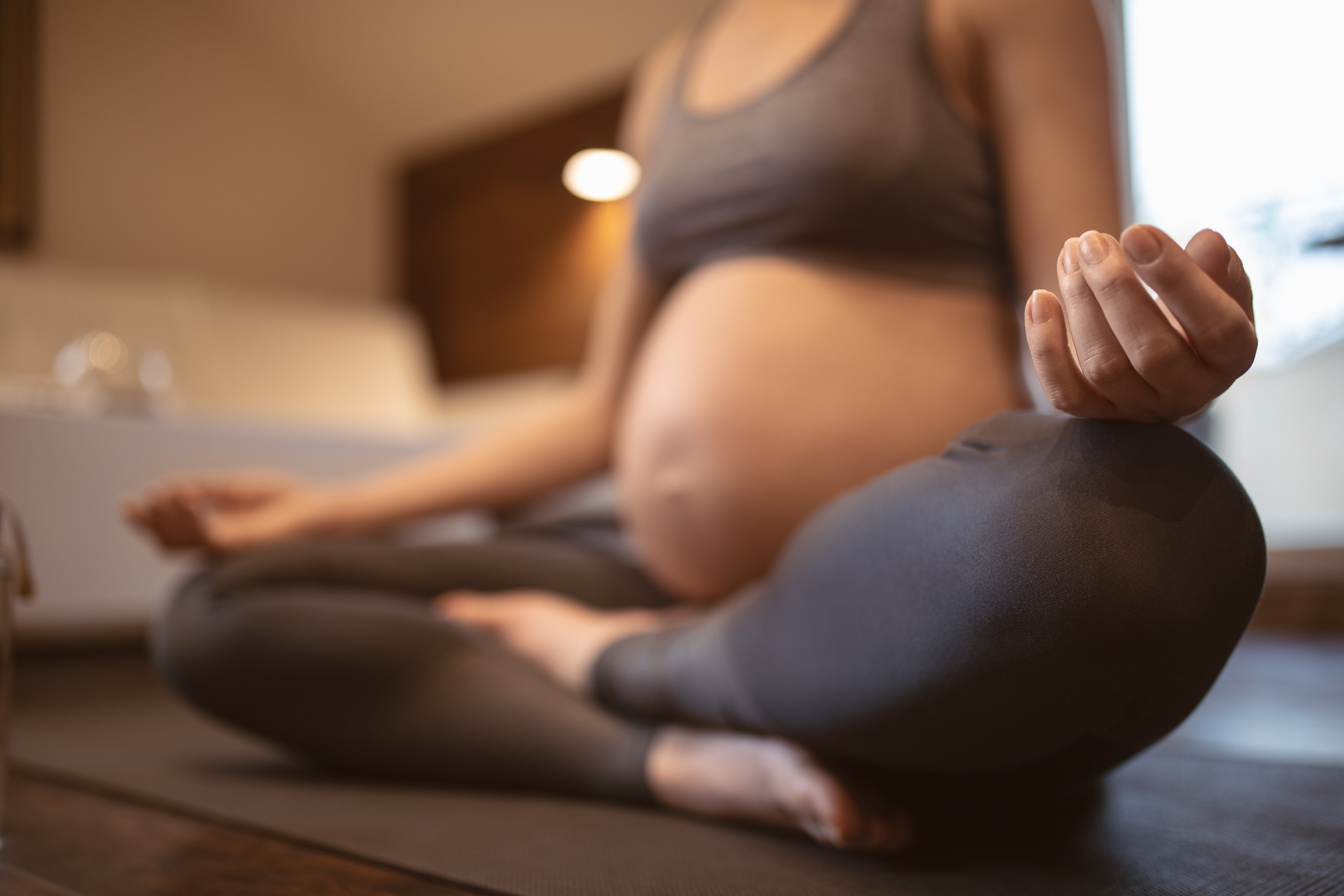 Young pregnant woman doing prenatal yoga at home